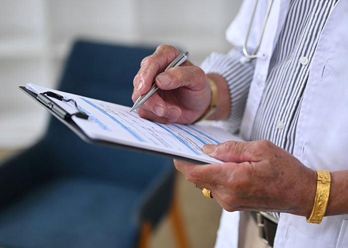 Doctor wearing a white coat writing notes on a clipboard, revealing unexpected industry secrets in a medical setting.