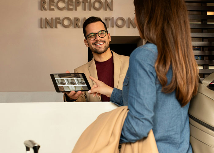 Receptionist showing a tablet to a guest at the information desk, illustrating industry secrets in customer service.