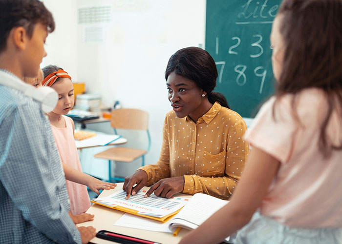 Teacher explaining unexpected industry secrets to a group of students in a classroom setting with a chalkboard behind.