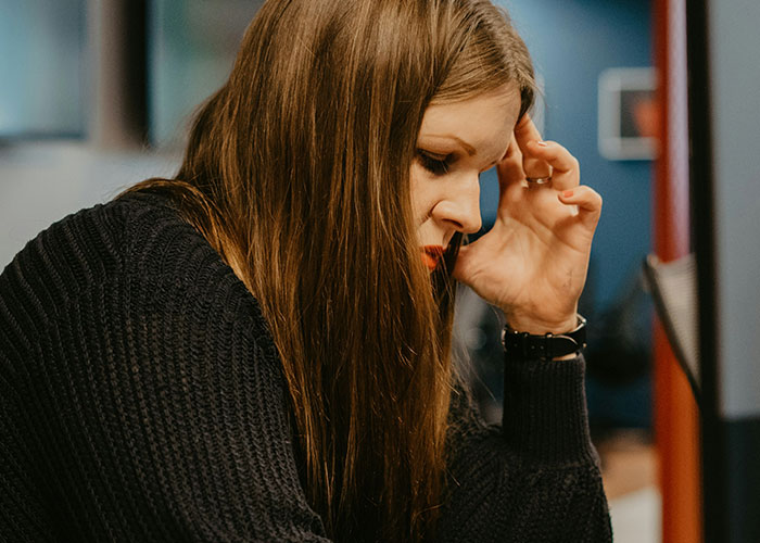 Young woman with long hair wearing a black sweater, focusing deeply while reflecting on industry secrets and business insights.