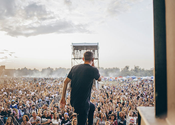Performer engaging a large crowd at an outdoor event, illustrating unexpected industry secrets in entertainment.