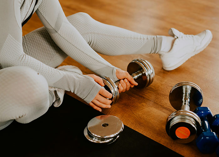 Person in textured workout clothes holding dumbbells, highlighting industry secrets in fitness and training routines.