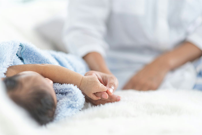 Newborn baby holding adult hand gently, evoking feelings related to bizarre and paranormal experiences.