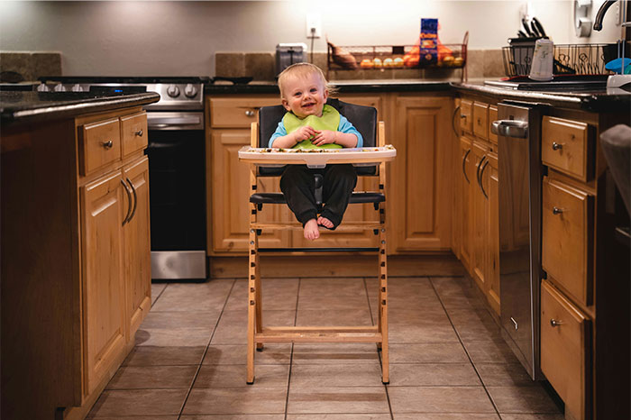 Baby sitting in a high chair in a kitchen, capturing a moment related to bizarre and paranormal experiences.