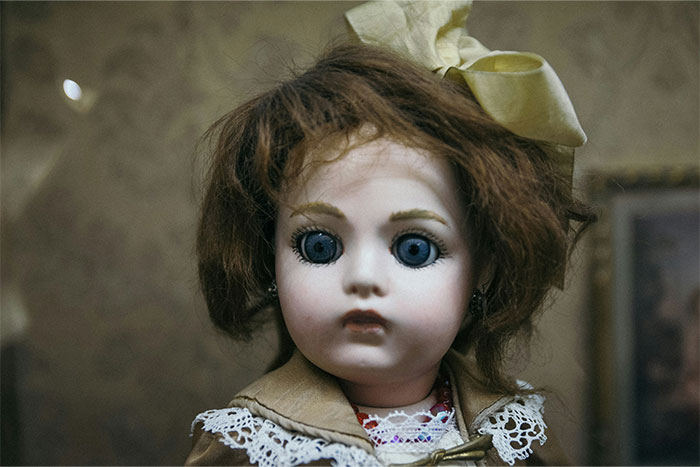 Antique porcelain doll with large blue eyes and brown hair, evoking bizarre and paranormal experiences.