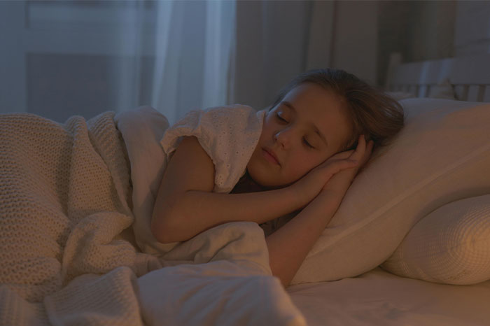 Young girl sleeping peacefully in bed at night, evoking themes of bizarre and paranormal experiences.