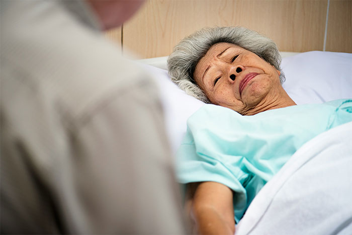 Elderly woman lying in hospital bed with a concerned expression, hinting at bizarre and paranormal experiences.