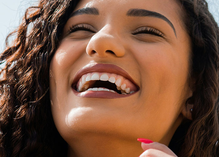 Close-up of a smiling woman with curly hair showcasing unique body quirks that highlight the fascinating human body.