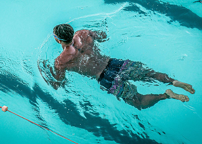 Man swimming underwater in a pool illustrating weird body quirks related to the fascinating human body.