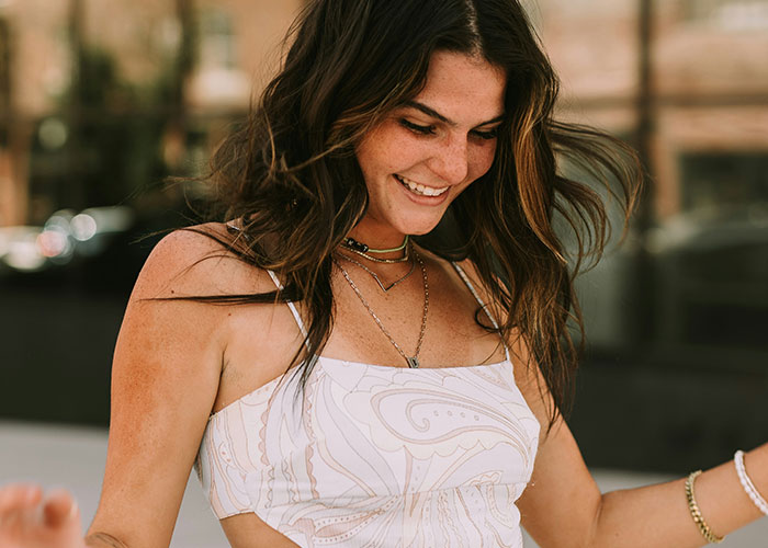 Smiling woman outdoors showing human body quirks with natural expression, highlighting fascinating body reactions.