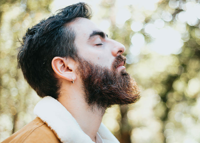 Profile of a bearded man with eyes closed outdoors illustrating weird body quirks of the human body fascination.