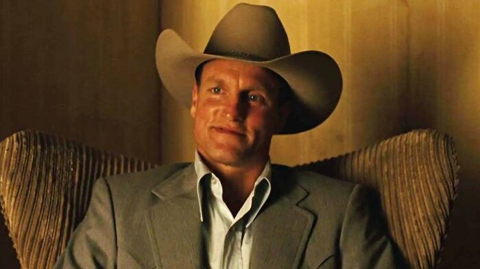 Actor wearing a cowboy hat and suit sitting in a chair, depicting a memorable meeting moment with an idol.