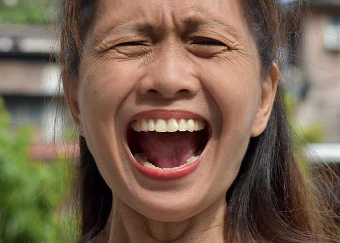 Close-up of a woman with eyes closed and mouth wide open, expressing shock and distress during a difficult vacation experience.