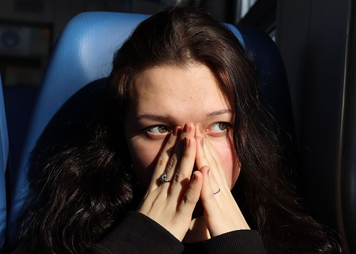 Young woman with worried expression covering her mouth, reflecting on vacations that ended up being trips to hell.