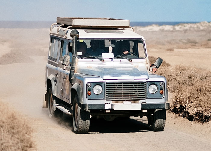 Off-road vehicle driving through dusty desert terrain, illustrating vacations that turned into difficult trips to hell.