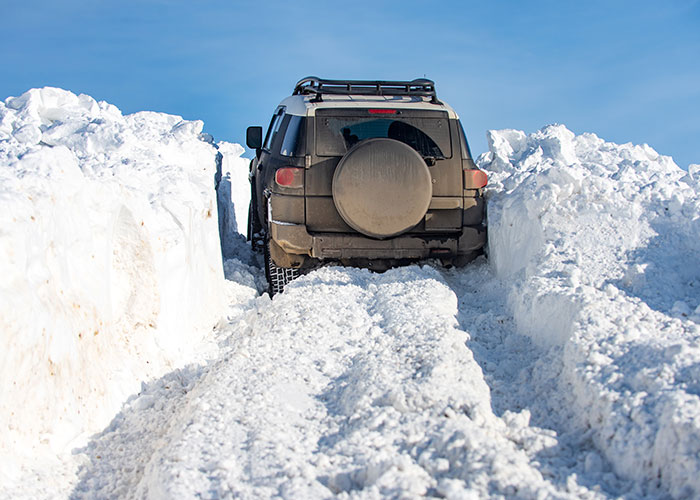 SUV stuck in deep snow on a narrow mountain road illustrating vacations that ended up being trips to hell.