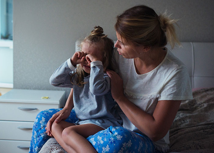 Mother comforting her young daughter upset after nightmares during a difficult vacation experience.