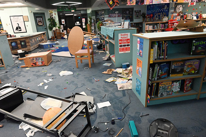 Library interior in disarray with overturned furniture and scattered debris, showcasing aftermath tied to two mothers turning in children to police.