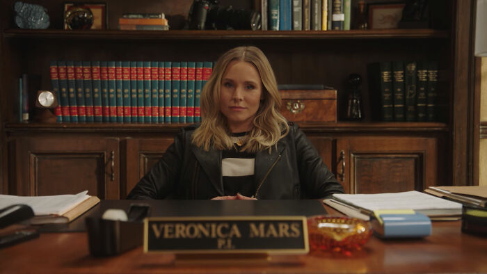 Female character in a leather jacket sitting confidently behind a desk, representing well-written female characters in movies.