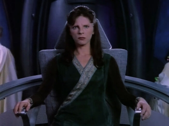 Female character in movie seated in futuristic chair, representing well-written female characters breaking stereotypes.