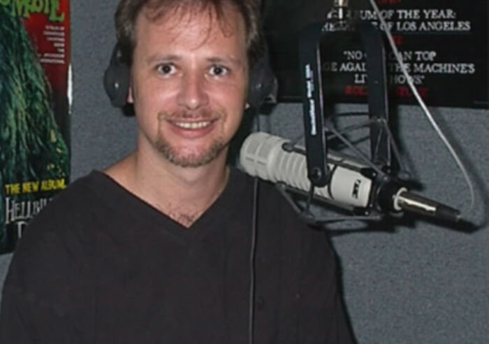 Man wearing headphones and smiling while speaking into a microphone, related to unexplained mysteries from the dawn of the internet.