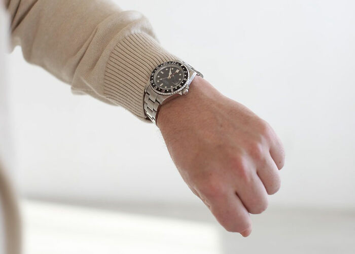 Close-up of a person wearing a silver wristwatch and beige sweater, symbolizing timelessness of wild rules people grew up with.