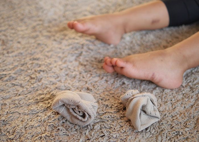 Bare feet and rolled-up socks on a carpet, illustrating one of the wildest rules people grew up with.