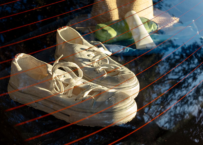 Worn white sneakers placed on a car rear window with reflections, illustrating wildest rules people grew up with.