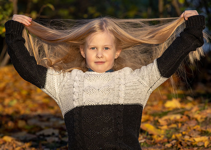 Young girl outdoors pulling her long hair, illustrating wildest rules people grew up with in an autumn setting.