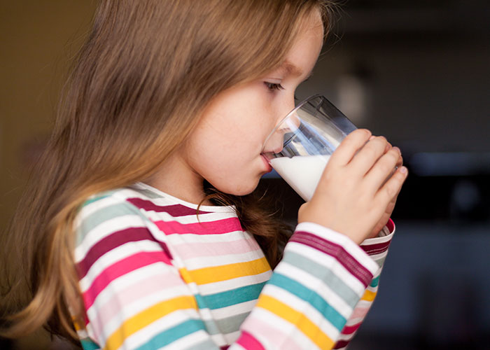 Young girl in striped shirt drinking milk, illustrating one of the wildest rules people grew up with today