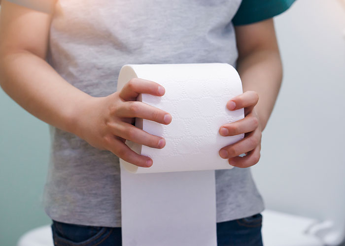 Child holding a roll of toilet paper illustrating one of the wildest rules people grew up with and still find confusing.