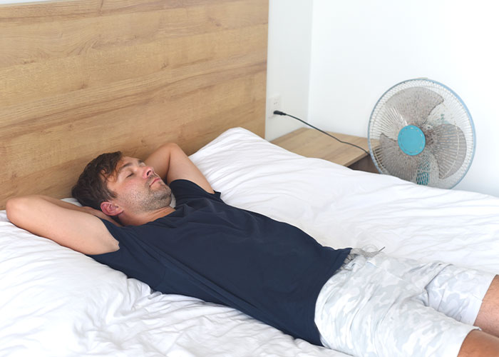 Man relaxing on a bed in a casual outfit, reflecting on wildest rules people grew up with in a simple bedroom setting.