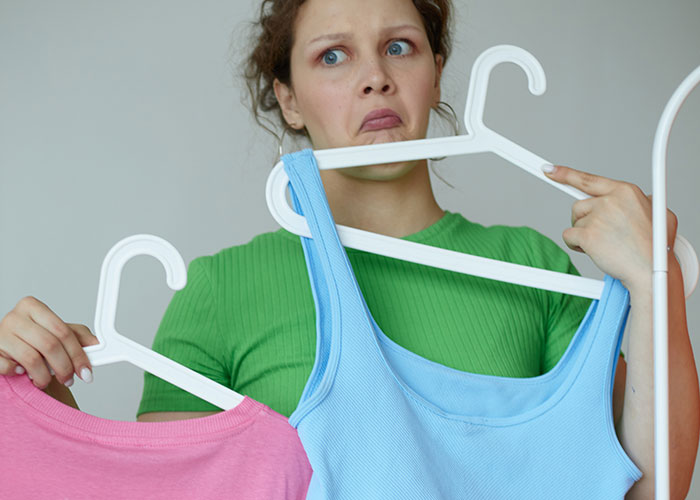 Woman in green shirt holding two clothes hangers with a confused expression about the wildest rules people grew up with