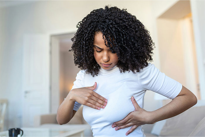 Woman examining her chest in a white shirt, illustrating patients trying to fool doctors with ridiculous lies.