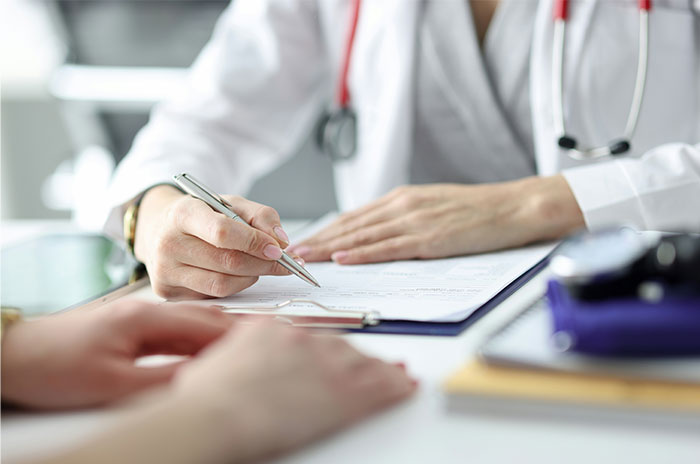 Doctor writing on clipboard during patient consultation, illustrating patients tried to fool doctors with ridiculous lies.