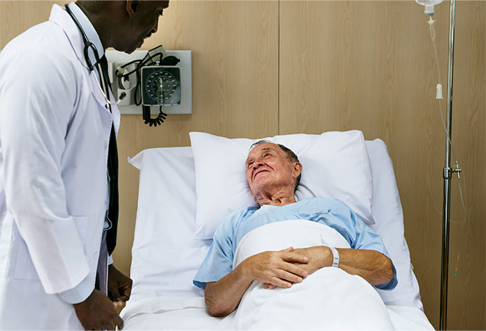 Doctor speaking with elderly patient in hospital bed, illustrating patients trying to fool doctors with ridiculous lies.