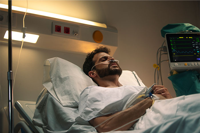 Patient lying in hospital bed with nasal oxygen, monitoring vital signs, illustrating patients trying to fool doctors with lies.