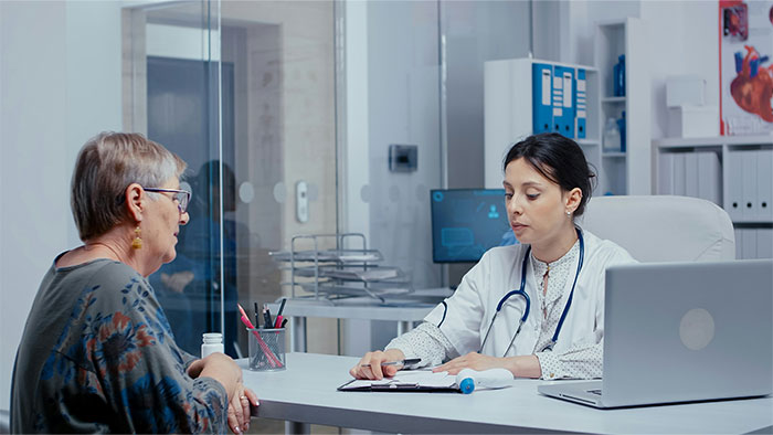 Doctor consulting an older female patient in an office as patient tries to fool doctor with ridiculous lies.