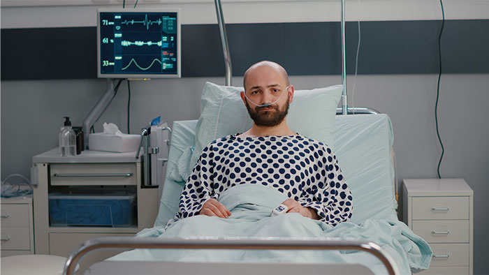 Patient in hospital bed wearing a nasal cannula, surrounded by medical equipment, illustrating patients trying to fool doctors.