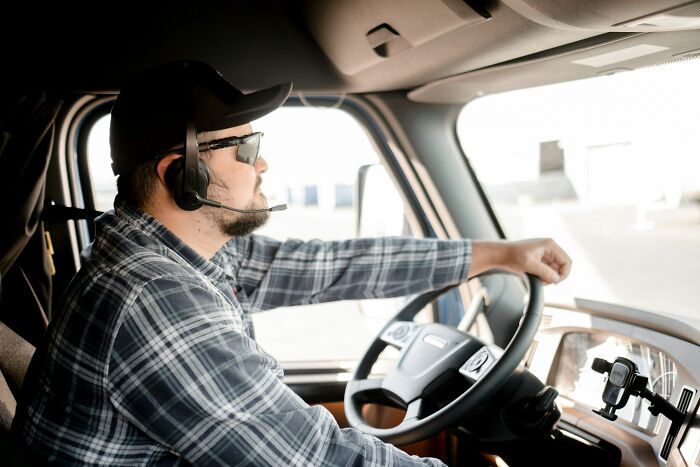 Man wearing headset and sunglasses driving a truck, representing professions often seen as not relationship material.