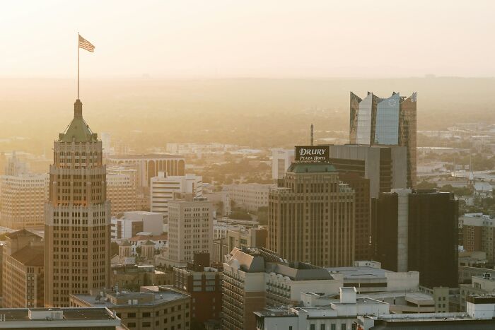City skyline at sunset showcasing popular travel destinations and urban landmarks with a hazy sky background.