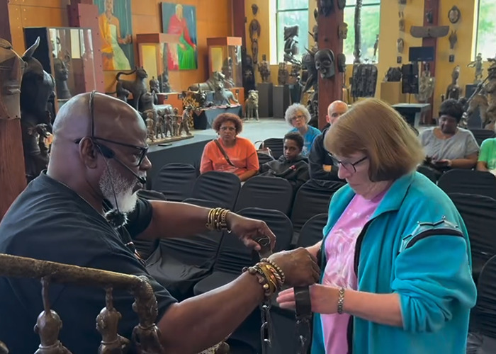 Man placing shackles on a white woman during an interactive exhibit at an African-American museum visit.