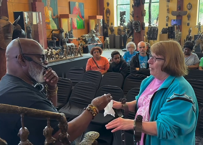 Woman wearing shackles during an African-American museum visit, showing a dramatic reaction while interacting with a guide.