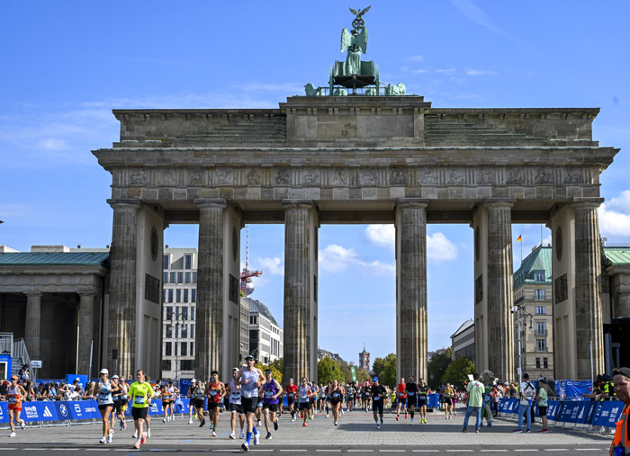 Runners participating in the Berlin Marathon passing under the Brandenburg Gate during the race event.