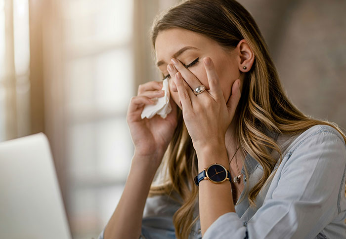 Woman with long hair wiping tears from her face, showing emotional wife&rsquo;s reaction to husband attending sister&rsquo;s baby shower.