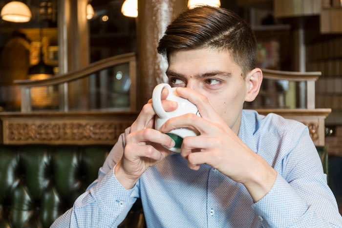 Man drinking coffee inside a caf&eacute;, highlighting issues with caf&eacute; rigid rules after wife with allergies stood outside during date.