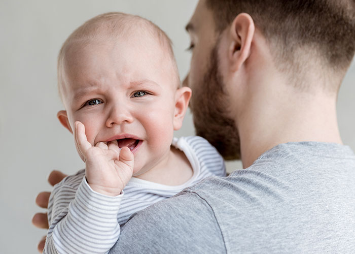 Father holding upset baby in nursery as mom realizes husband has a problem and starts building an exit plan Father holding upset baby in nursery as mom realizes husband has a problem and starts building an exit plan