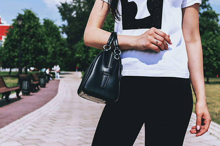 Woman holding black purse outdoors in a park, illustrating purse fiasco and friendship ending after 15 years.