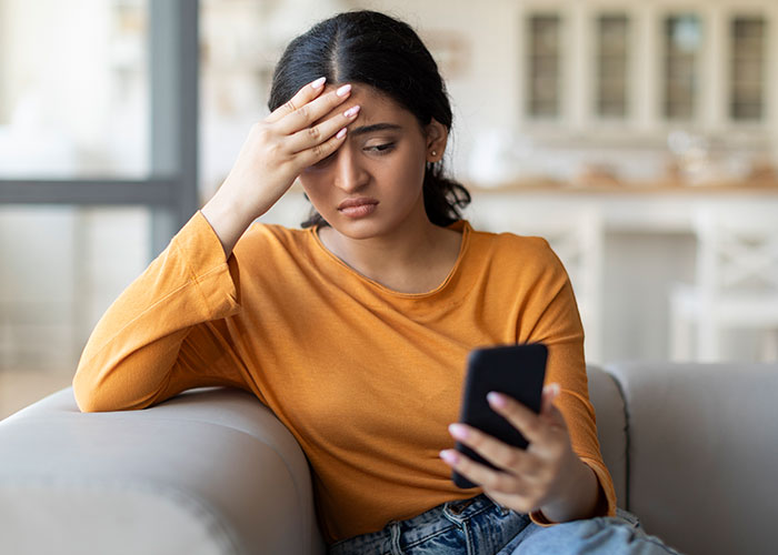 Woman in orange shirt looking distressed while holding a phone, reflecting feelings of being a backup choice in a relationship. Woman in orange shirt looking distressed while holding a phone, reflecting feelings of being a backup choice in a relationship.