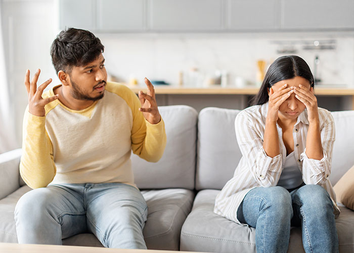 Couple having an argument on couch, woman upset and covering face, reflecting emotional pain of being second choice backup. Couple having an argument on couch, woman upset and covering face, reflecting emotional pain of being second choice backup.